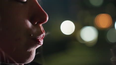 urban dweller sipping water from transparent sports bottle under blurred city lights at twilight while recovering from intense workout on outdoor bench with calm focused expression