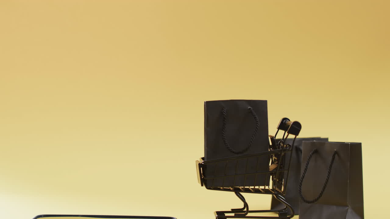 vídeo de smartphone, sacos de compras e carrinho com espaço de cópia em fundo amarelo