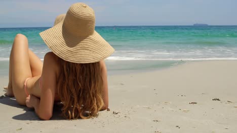 Rear-view-of-Caucasian-woman-in-hat-relaxing-on-the-beach-4k