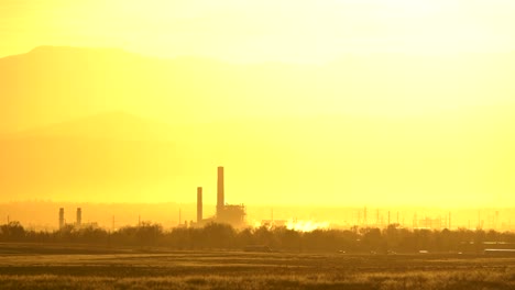 Industrial-facility-emitting-smoke-against-a-background-of-mountains