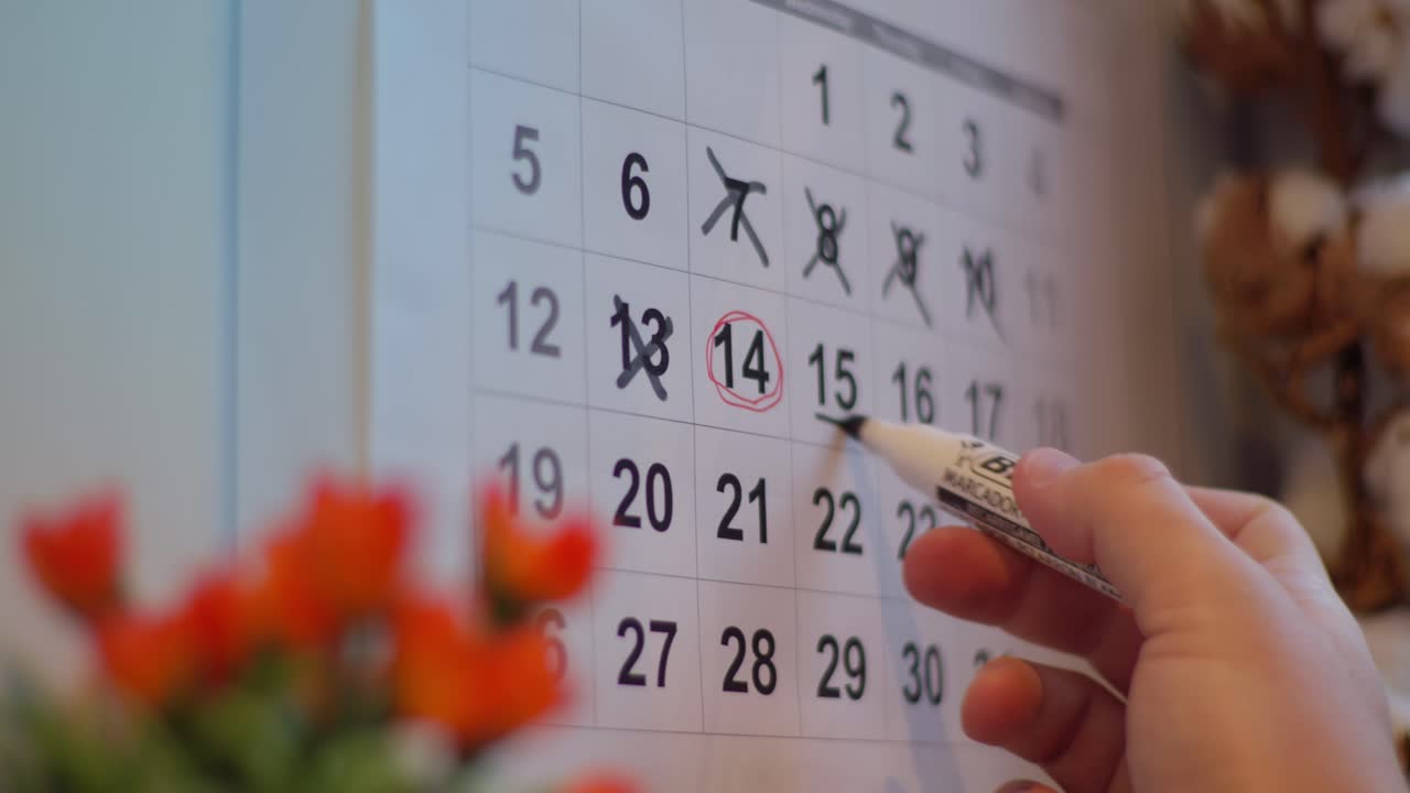 Nærbillede af en hånd, der markerer vigtige datoer på en kalender