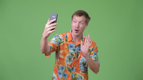 joven turista guapo llamando en video y mostrando el teléfono