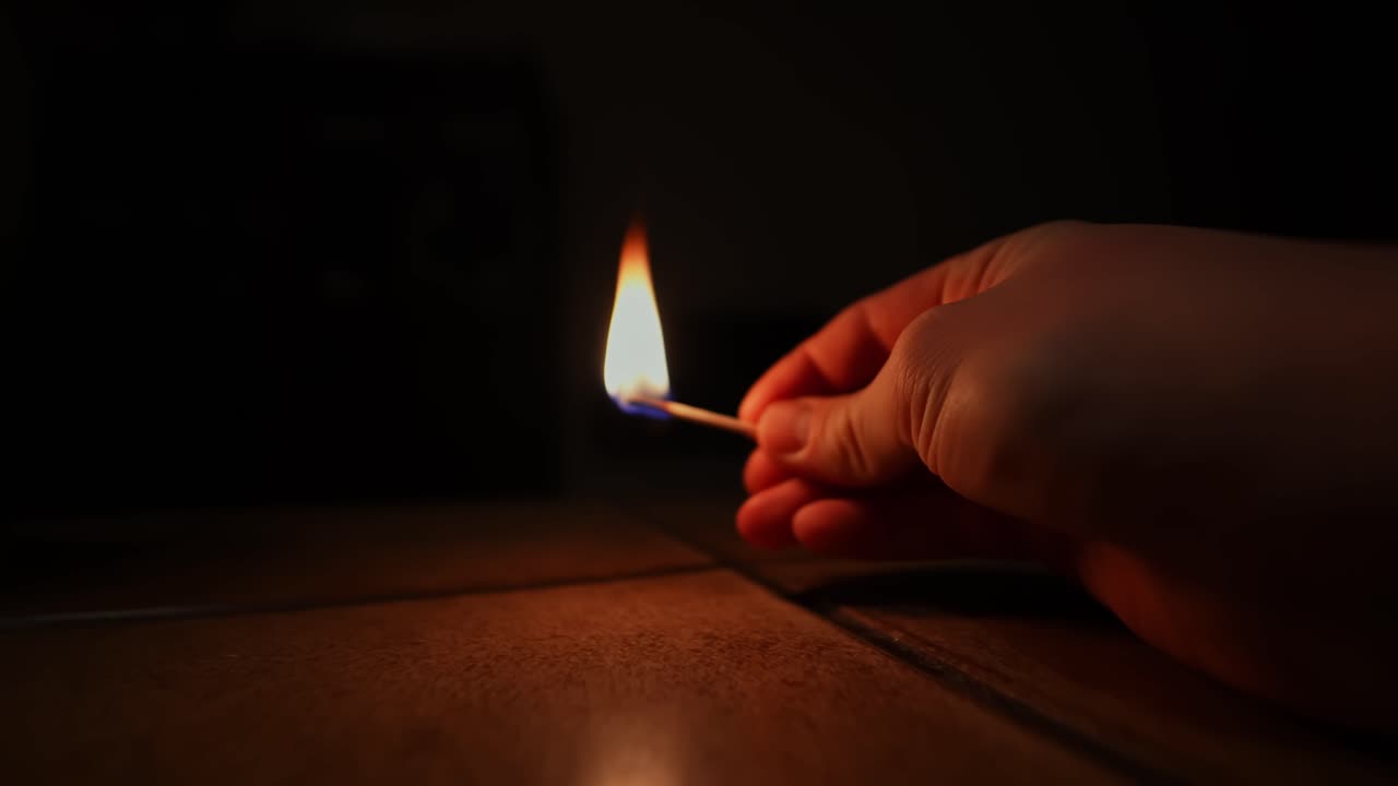 Encender una cerilla en una habitación oscura crea un ambiente cálido y sombrío.