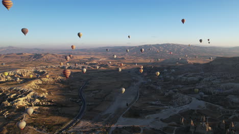 aerial view of hot air balloons above magical landscape of cappadocia, turkey on sunny morning, drone shot