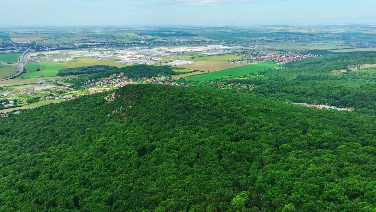 Beautiful drone shot from Zobor hill capturing the panoramic view of Nitra city, forested hills, and surrounding farmland in Slovakia