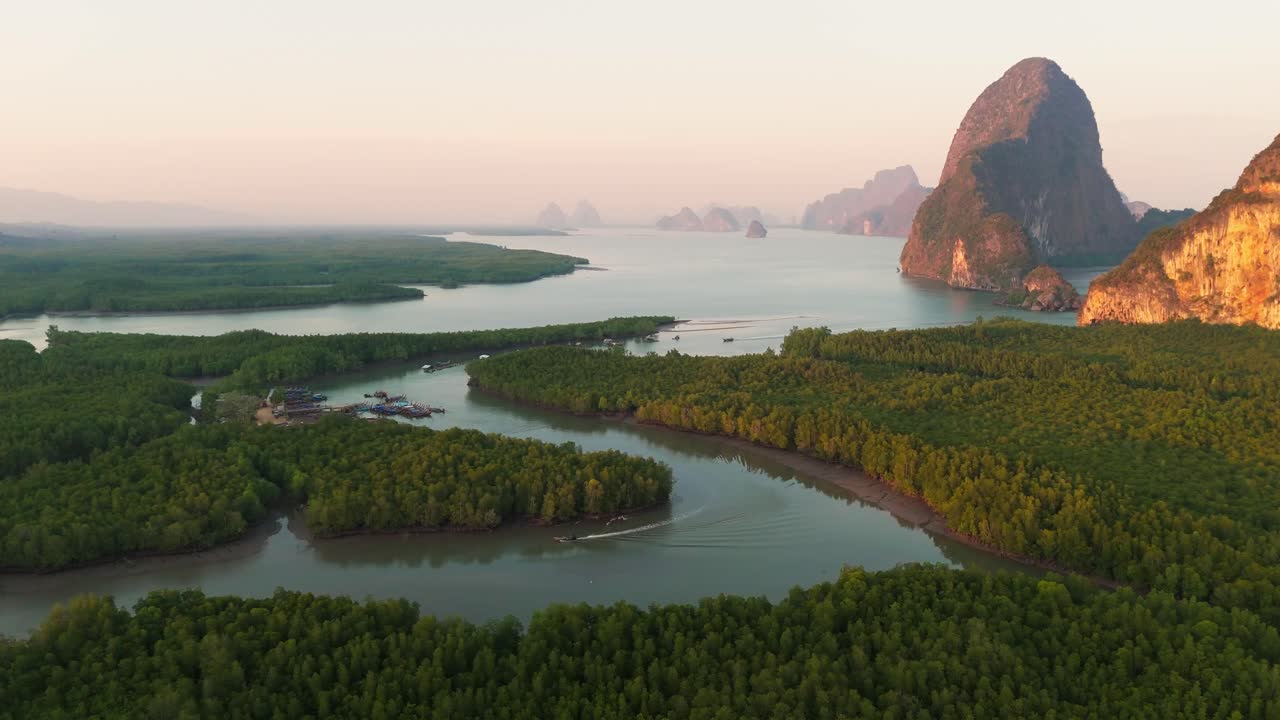 Stunning drone flight over lush tropical forest in Southeast Asia, with Karst Mountains in background at sunrise.