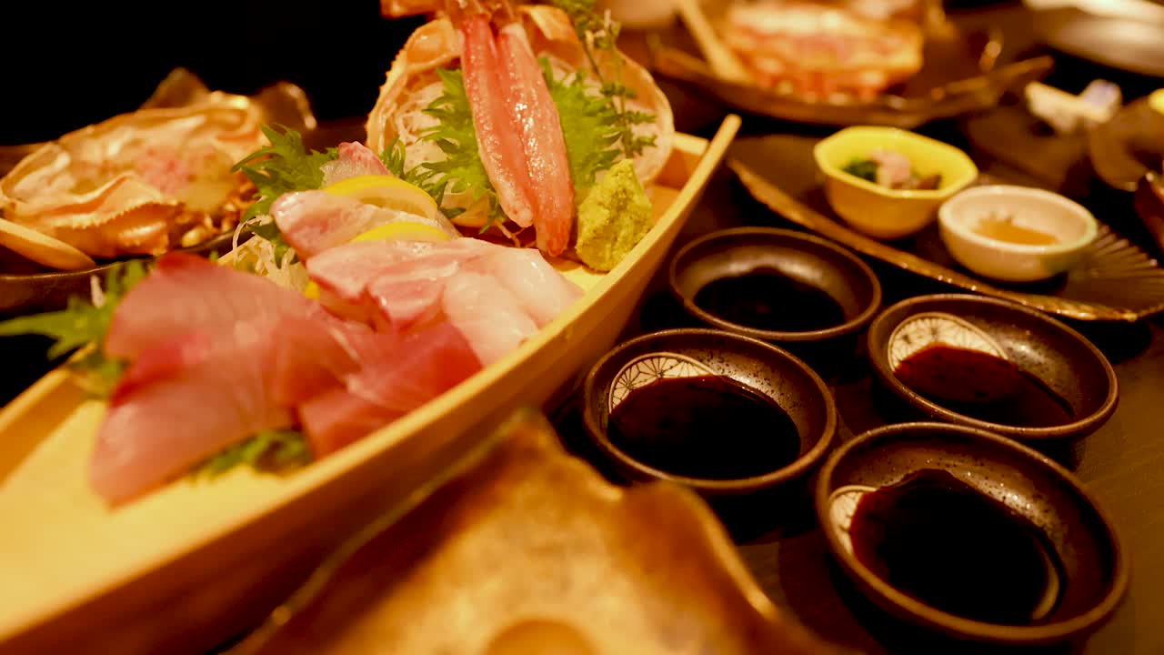Primo piano di pesce crudo, zampe di granchio e wasabi disposti su un piatto a forma di barca in legno.