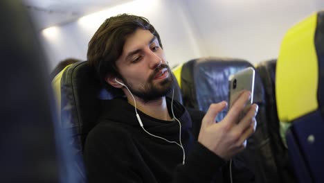 young man listening to music on headphones via cell phone
