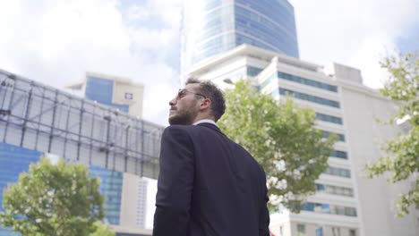 Businessman-walking-against-high-rise-business-centers.