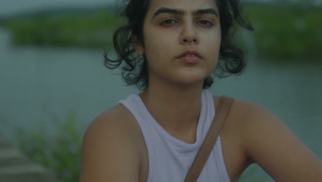 In-slow-motion,-a-captivating-young-Indian-woman-stands-beside-a-tranquil-river