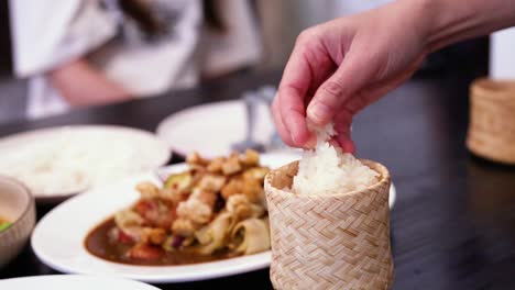 hand serving sticky rice with thai dish