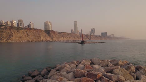 push in shot at sunset to a single excavator machine building a stone pier in the sea