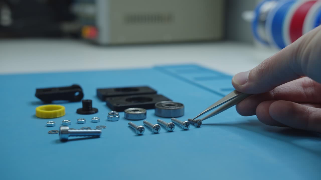 colocación de tornillo con pinzas junto a piezas pequeñas