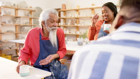 Happy-diverse-group-of-potters-discussing-and-laughing-in-pottery-studio