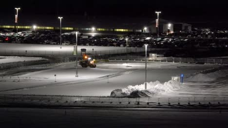 a snowplow clears an airport parking lot at night in toronto, canada, timelapse