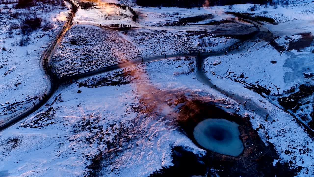 아이슬란드 게이시르의 게이저 위의 파노라마 뷰: 은 해가 지는 에 사람들이 게이저를 둘러싸고 고 있는 게이저에서 연기가 어나오고 있다.