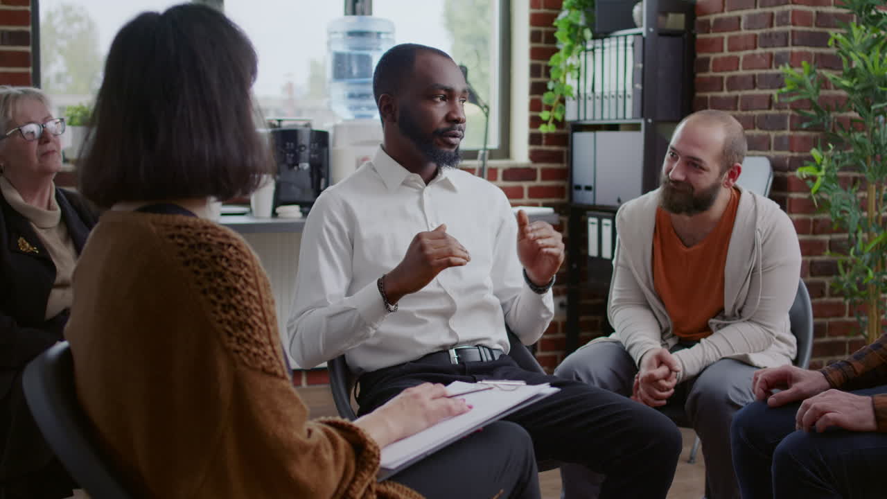 African american man sharing addiction story with group of people at aa therapy meeting