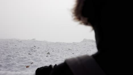 mujer mirando una montaña, paisaje nevado detrás de las nubes, vista por encima del hombro