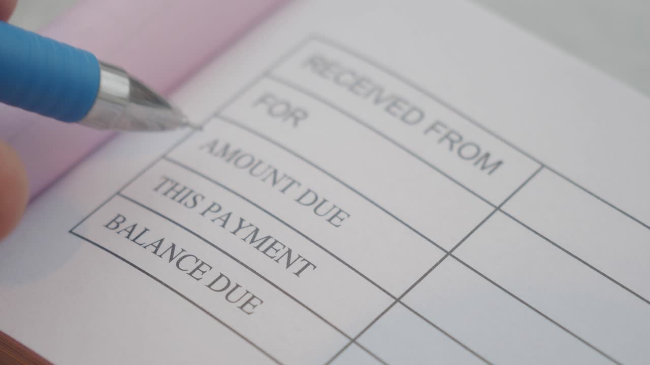 persona que escribe en un libro de recibos financieros