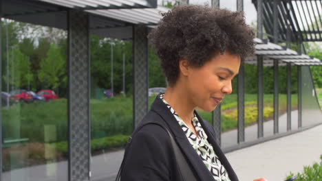 businesswoman outside modern office building checking messages on mobile phone