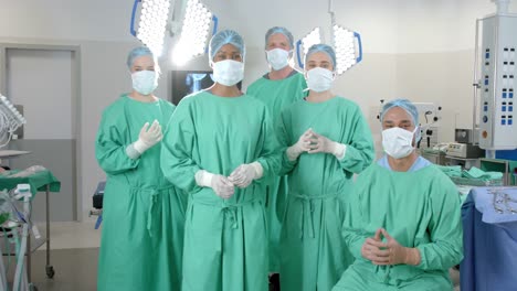 portrait of diverse surgeons wearing surgical gowns in operating theatre, slow motion