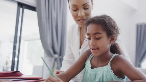 madre y hija afroamericanas sentadas en la mesa y haciendo la tarea juntas, cámara lenta