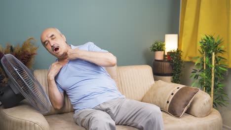 el anciano que usa el ventilador está abrumado por el calor.