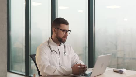 Close-up-portrait-of-a-male-doctor-conducting-an-online-consultation-on-a-laptop