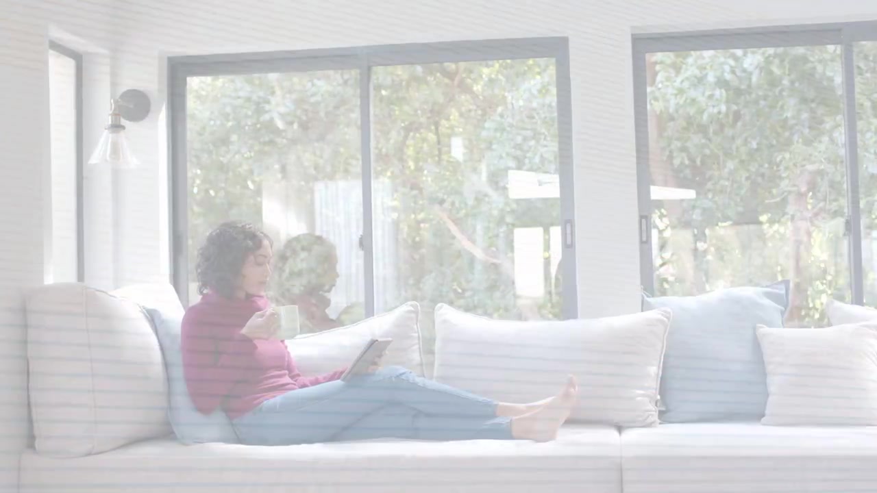 Sin interferencias, mujer sentada en el sofá, leyendo una tableta y bebiendo de una taza, relajándose en casa