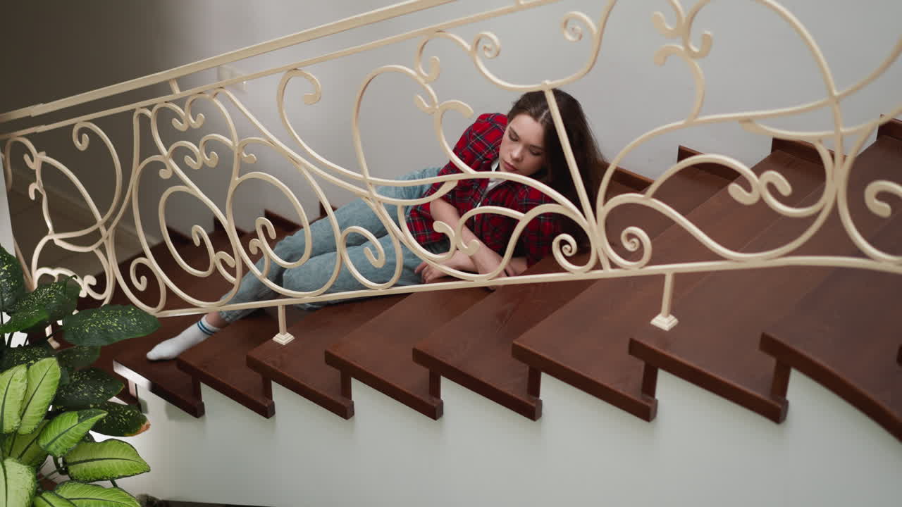 una mujer triste yace en los escalones de una casa residencial. una mujer frustrada con síntomas de estrés y trauma descansa en las escaleras. salud mental y psicología