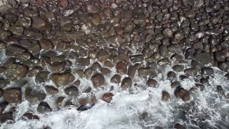 foamy blue waves crushing into rocky shore, view from above