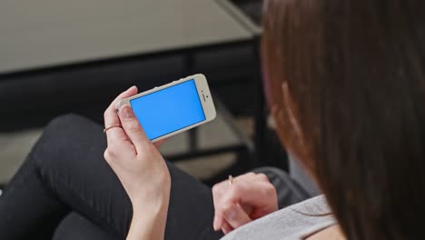 mujer sostiene un teléfono inteligente con pantalla azul