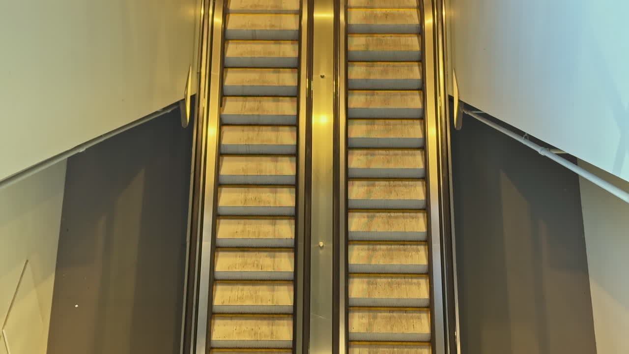 Escaleras mecánicas en un edificio público se mueven entre dos niveles en un centro comercial durante el día