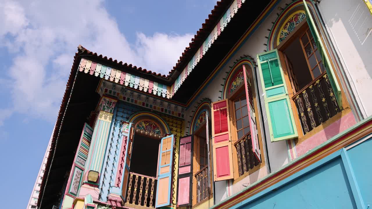 Two women walk past a vibrant, historic blue building with ornate windows in daylight