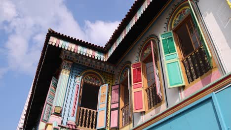 two women walk past a vibrant, historic blue building with ornate windows in daylight