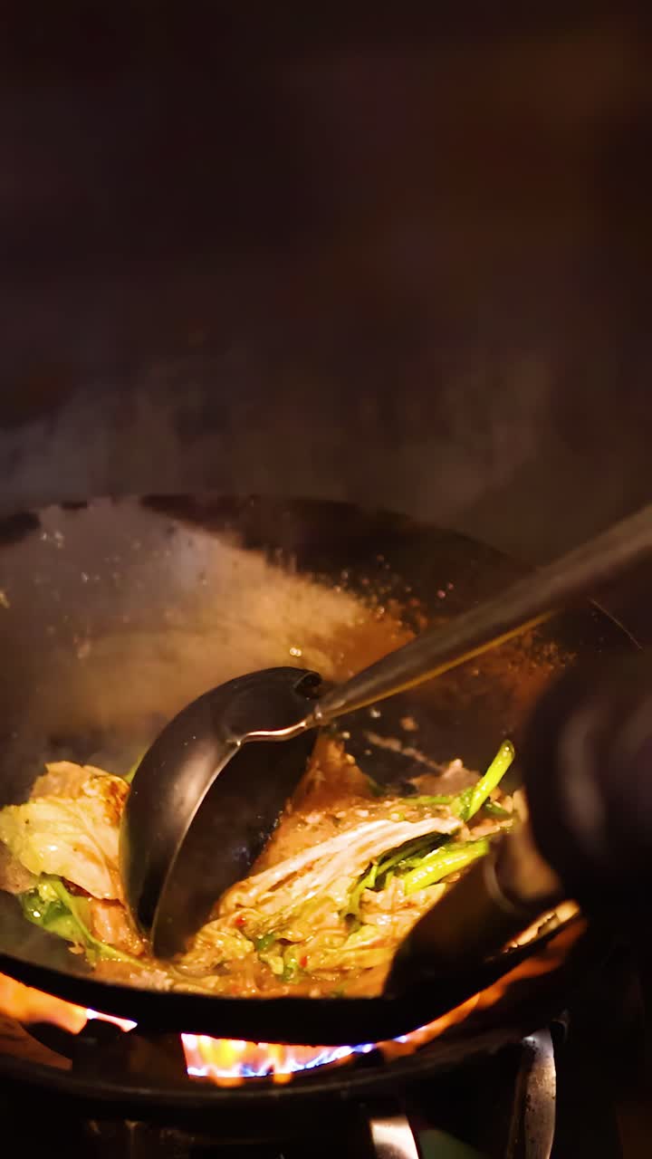 Uno chef salta in padella sukiyaki con verdure e noodles in un wok caldo, in stile street food.