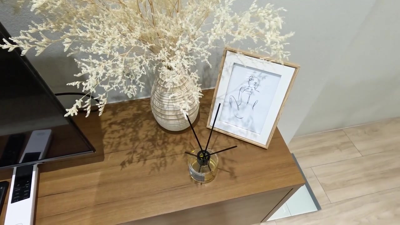 Arredamento elegante per la casa con fiori secchi, opere d'arte e diffusore su un mobile in legno.