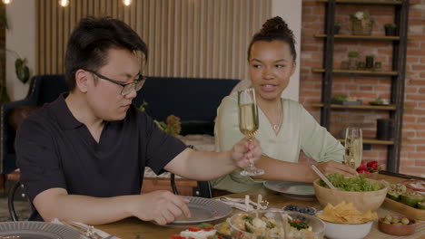 un joven y una chica bonita brindan sus bebidas antes de una comida 1