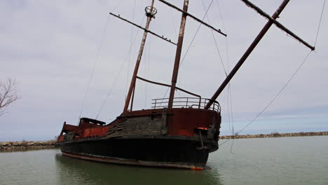 rusty red shipwreck stuck in shallow green water