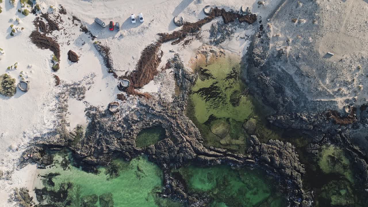 Drone footage of El Cotillo’s volcanic coastline in Fuerteventura, with ocean waves breaking against dark rocks on the rugged Atlantic shore.
