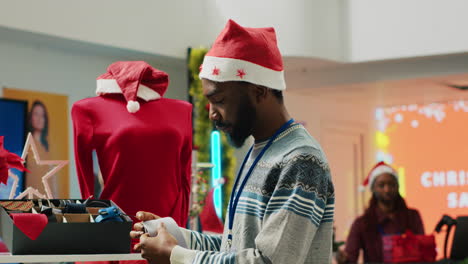 manager wearing santa hat arranging formal attire neckties in christmas decorated clothing store. supervisor inspecting accesories in xmas adorn shop during winter holiday season