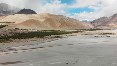 river crossing thought a big empty desert area with majestic mountains and cloudy sky in shyok, ladakh, india