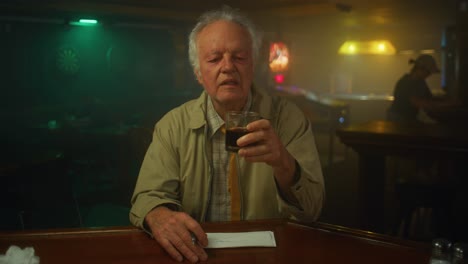 man drinks at a dingy bar alone