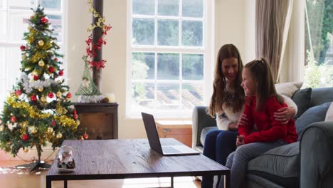 Madre-E-Hija-Caucásicas-Sonriendo-Y-Saludando-Mientras-Hacen-Una-Videollamada-En-Una-Computadora-Portátil-Sentada-En-El