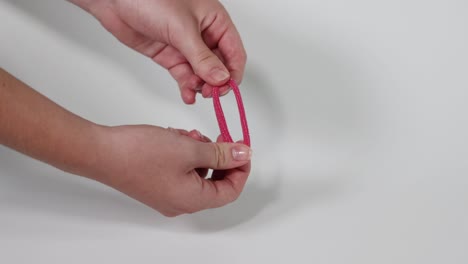 hands stretching a pink hair tie