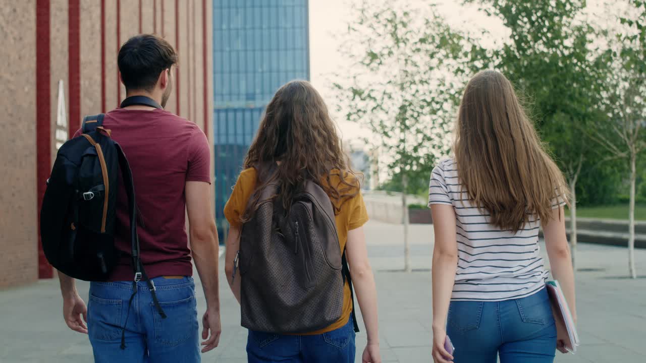 tres estudiantes caucásicos caminando por el campus de la universidad