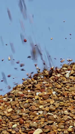 stones pouring from conveyor on pile - vertical shot