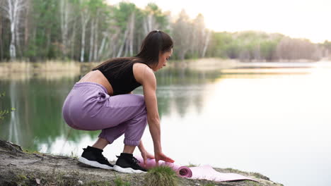 woman rolling a mat in the forest