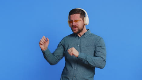 happy man in sunglasses listening music on headphones and dancing disco fooling around having fun