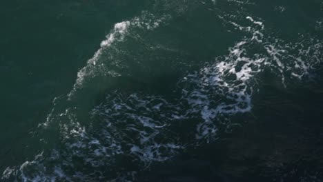 dark turquoise water surface with waves of a ship and its shawos in it